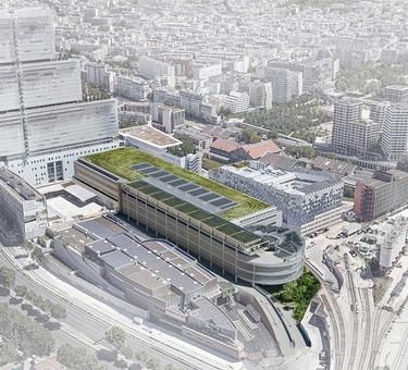 Flygbild av en tät stadsdel med stort grönt tak och trafikleder